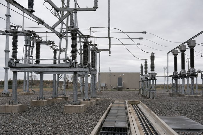 Patio de subestación de alta tensión con pórticos, seccionadores, transformadores de medida y canalización de cables.